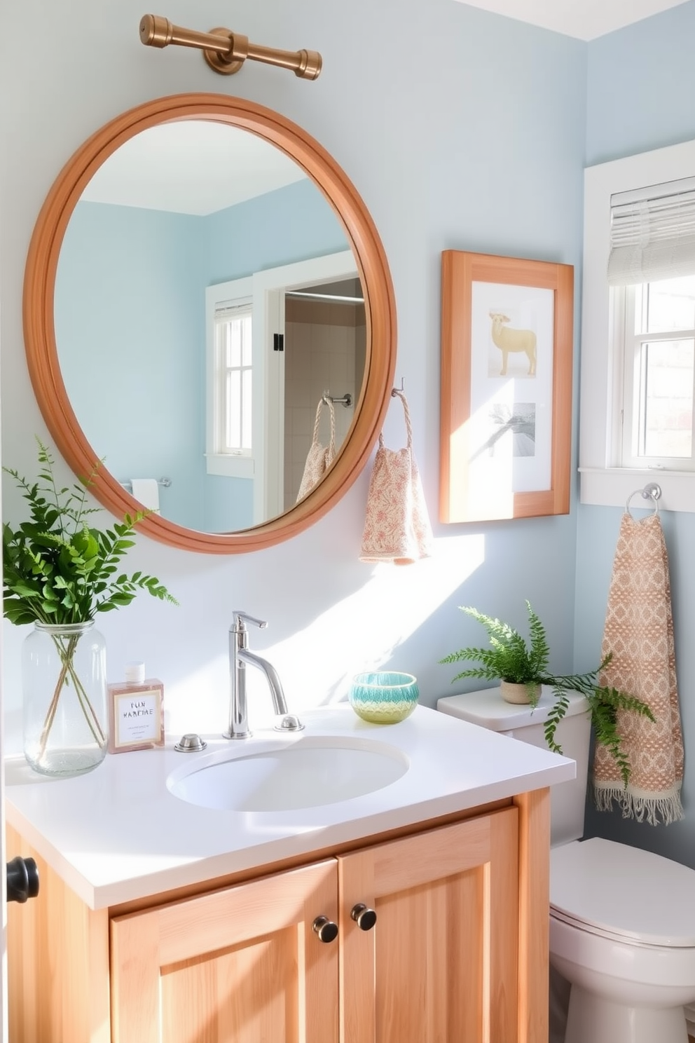 A light wood vanity with a white countertop creates a warm and inviting atmosphere. Above the vanity, a round mirror with a natural wood frame reflects the soft light from a nearby window. The walls are painted in a soft pastel blue, evoking a fresh summer feel. Accents of greenery and colorful towels add a cheerful touch to the overall decor.