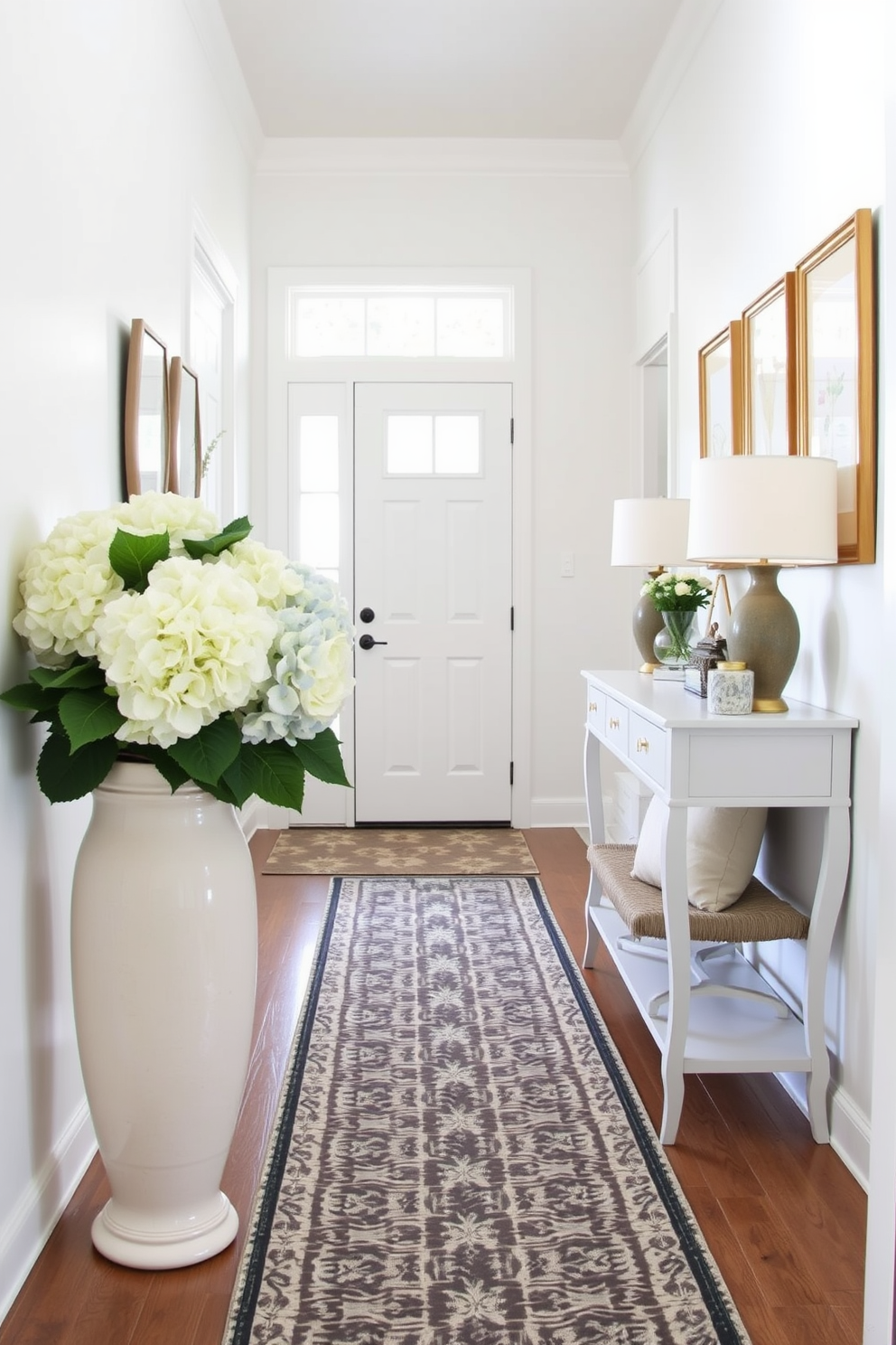 A bright and airy entryway adorned with faux hydrangeas in a large ceramic vase. The walls are painted a soft pastel color, and a stylish console table with decorative accents sits against one side. A patterned runner rug leads to the door, while a set of framed botanical prints hangs above the console. A cozy bench with throw pillows provides a welcoming touch, inviting guests to linger.