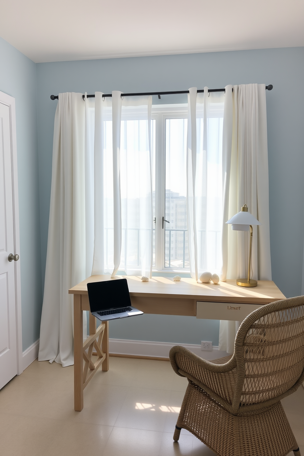 A bright and airy workspace inspired by coastal vibes. The room features a large window with sheer white curtains allowing natural light to flood in. A light wood desk is positioned facing the window, adorned with a sleek laptop and a few decorative seashells. The walls are painted a soft blue, and a comfortable rattan chair adds a touch of texture to the space.