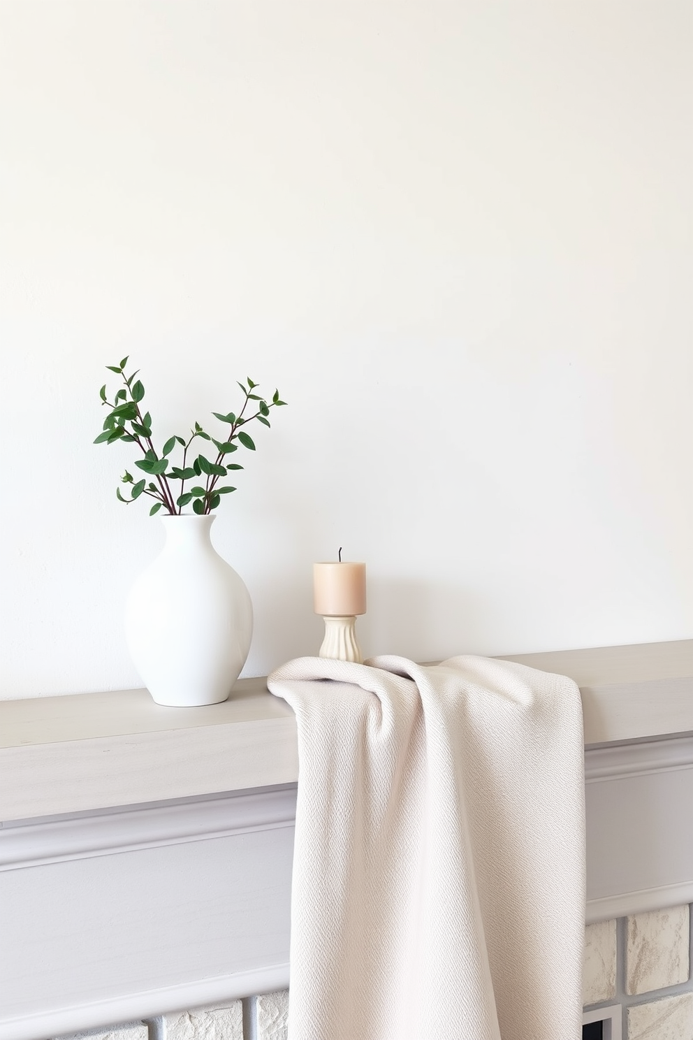 Create a minimalist look with few items. The mantel features a simple white ceramic vase with fresh greenery and a single decorative candle in a muted tone. A soft, neutral-colored throw blanket is casually draped over one end of the mantel. The backdrop is a light, airy wall that enhances the clean and uncluttered aesthetic.