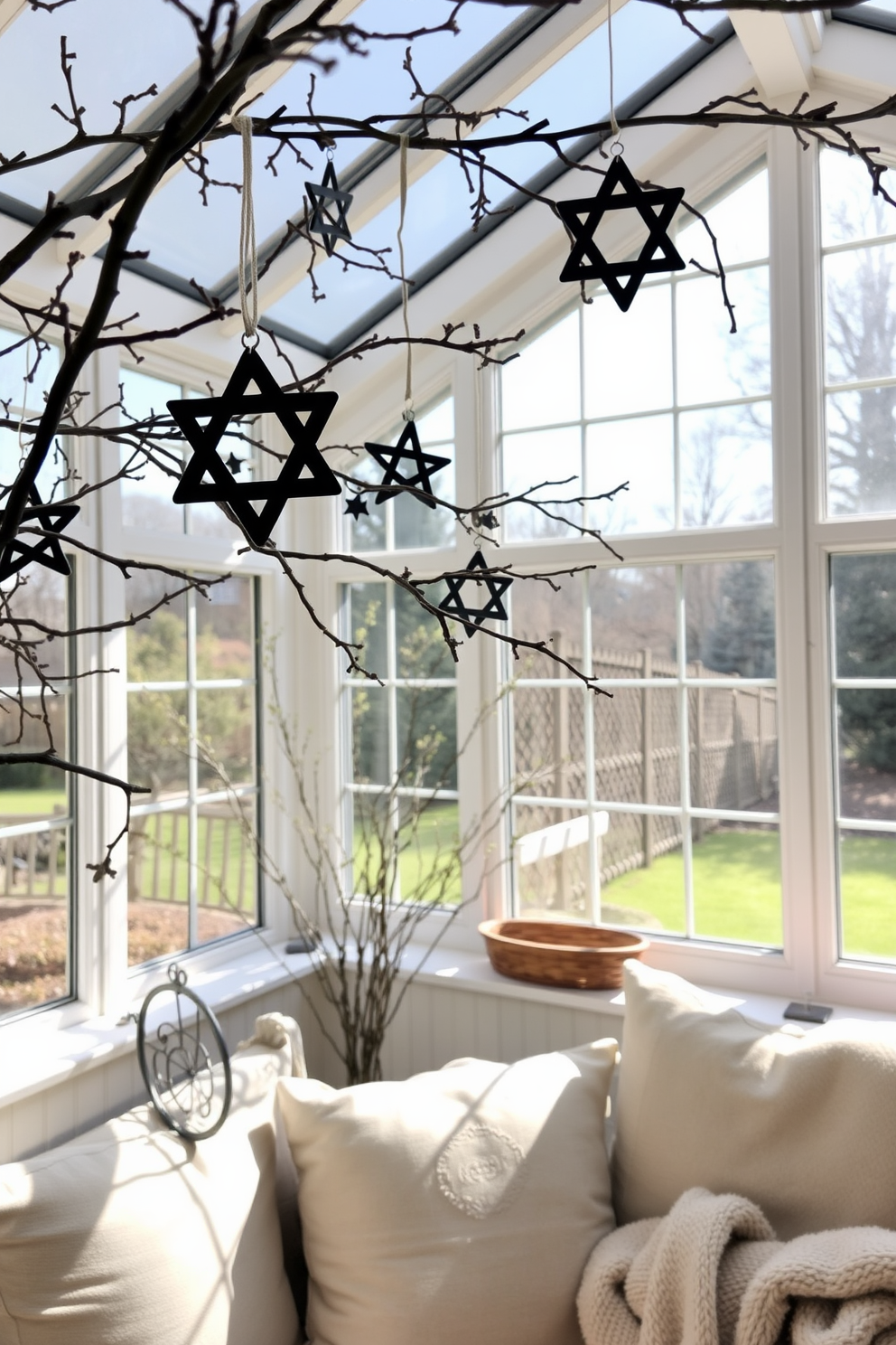 A sunroom filled with natural light features branches adorned with Star of David ornaments, creating a festive atmosphere. The space is decorated with soft cushions and a cozy throw, inviting relaxation and celebration during Hanukkah.