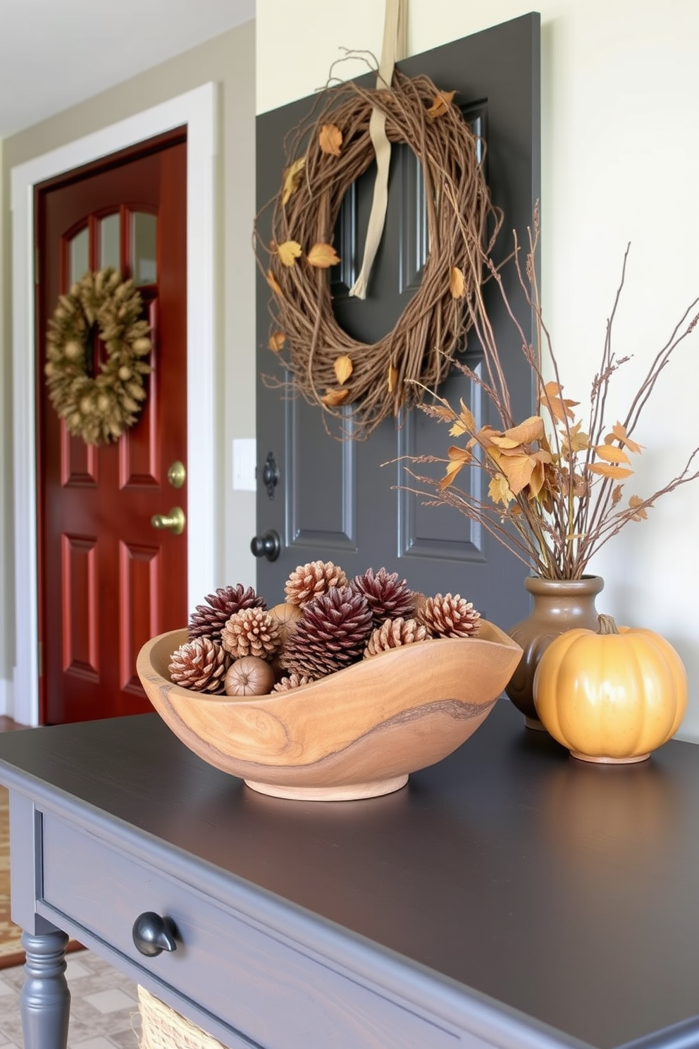 A welcoming entryway adorned with natural elements for Thanksgiving. Pinecones and acorns are artfully arranged in a rustic wooden bowl on a console table. A warm, inviting color palette complements the seasonal decor. A wreath made of twigs and dried leaves hangs on the door, enhancing the festive atmosphere.