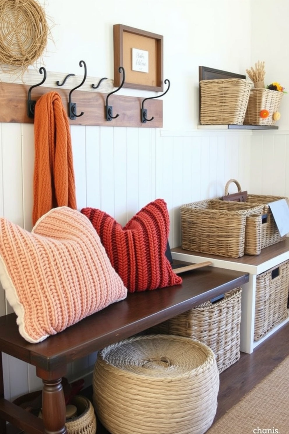 Layered textures create a warm and inviting atmosphere in a Thanksgiving mudroom. Soft knitted pillows in autumn colors are arranged on a bench, complementing the rustic wooden hooks and woven baskets for storage.