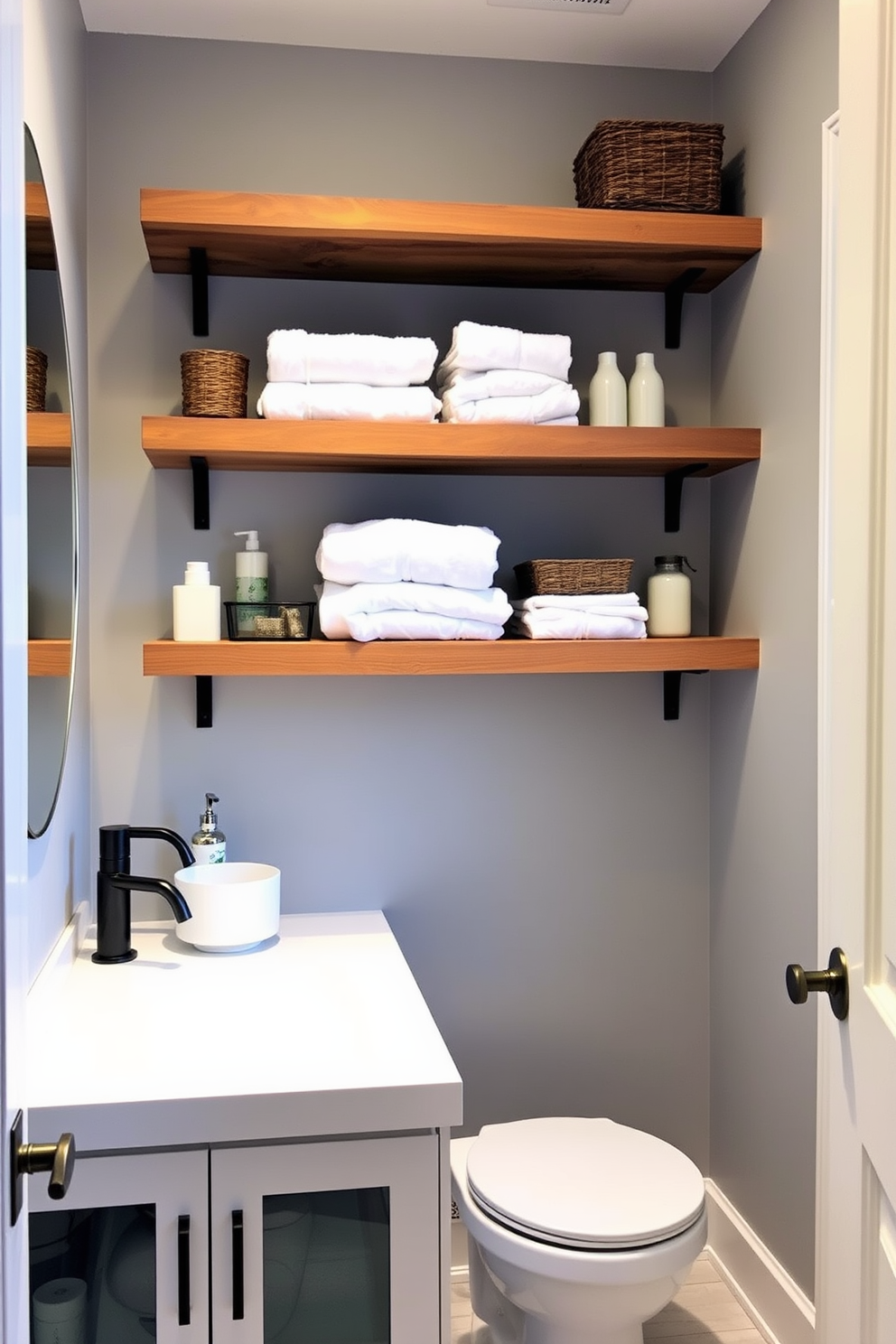 A modern three-quarter bathroom featuring open shelving for easy storage solutions. The shelves are made of reclaimed wood and are filled with neatly arranged towels, toiletries, and decorative baskets. The walls are painted in a soft gray hue, creating a calming atmosphere. A sleek white vanity with a vessel sink complements the overall design, while stylish fixtures add a touch of elegance.