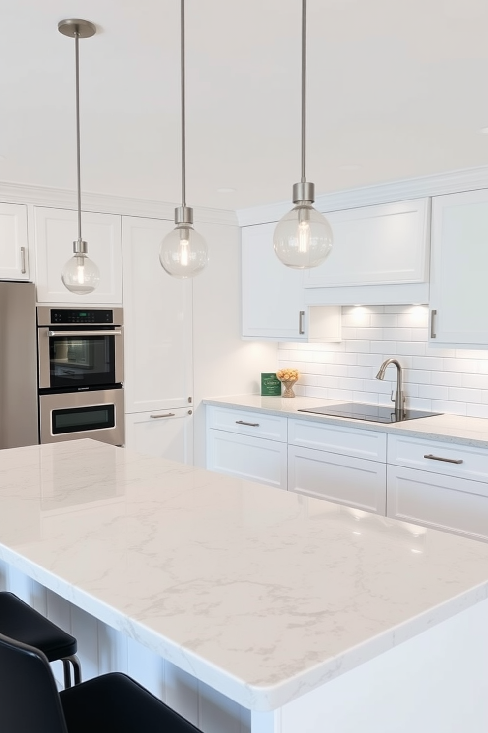 A modern kitchen featuring integrated appliances that blend seamlessly into the cabinetry. The design includes a spacious island with bar seating and a polished stone countertop, surrounded by minimalist cabinetry in a soft white finish. The kitchen is illuminated by pendant lights that hang above the island, adding a touch of elegance. A backsplash of subway tiles in a classic white color complements the overall timeless aesthetic of the space.