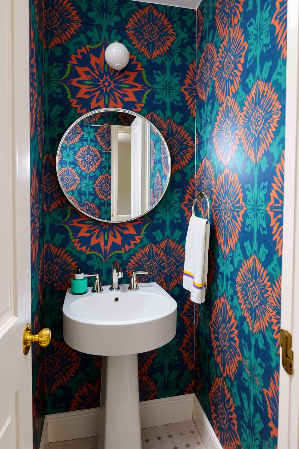 A tiny powder room designed to make a bold statement. The walls are covered in vibrant, patterned wallpaper that creates a dramatic focal point. A sleek pedestal sink is paired with a stylish wall-mounted faucet. A round mirror with an ornate frame hangs above the sink, enhancing the room's elegance.