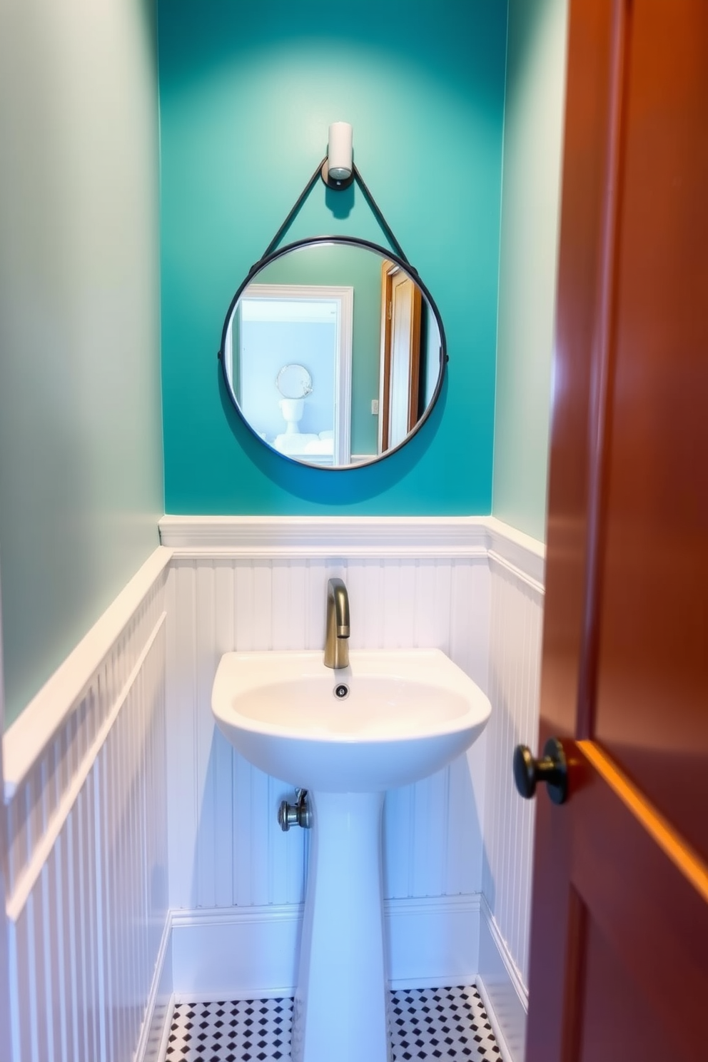 A striking accent wall painted in a vibrant teal creates a focal point in a tiny powder room. The remaining walls are adorned with soft white wainscoting, enhancing the room's brightness and spacious feel. A sleek pedestal sink is paired with a modern wall-mounted faucet, maximizing floor space. Above the sink, a round mirror with a thin black frame reflects the bold color of the accent wall, adding depth to the design.