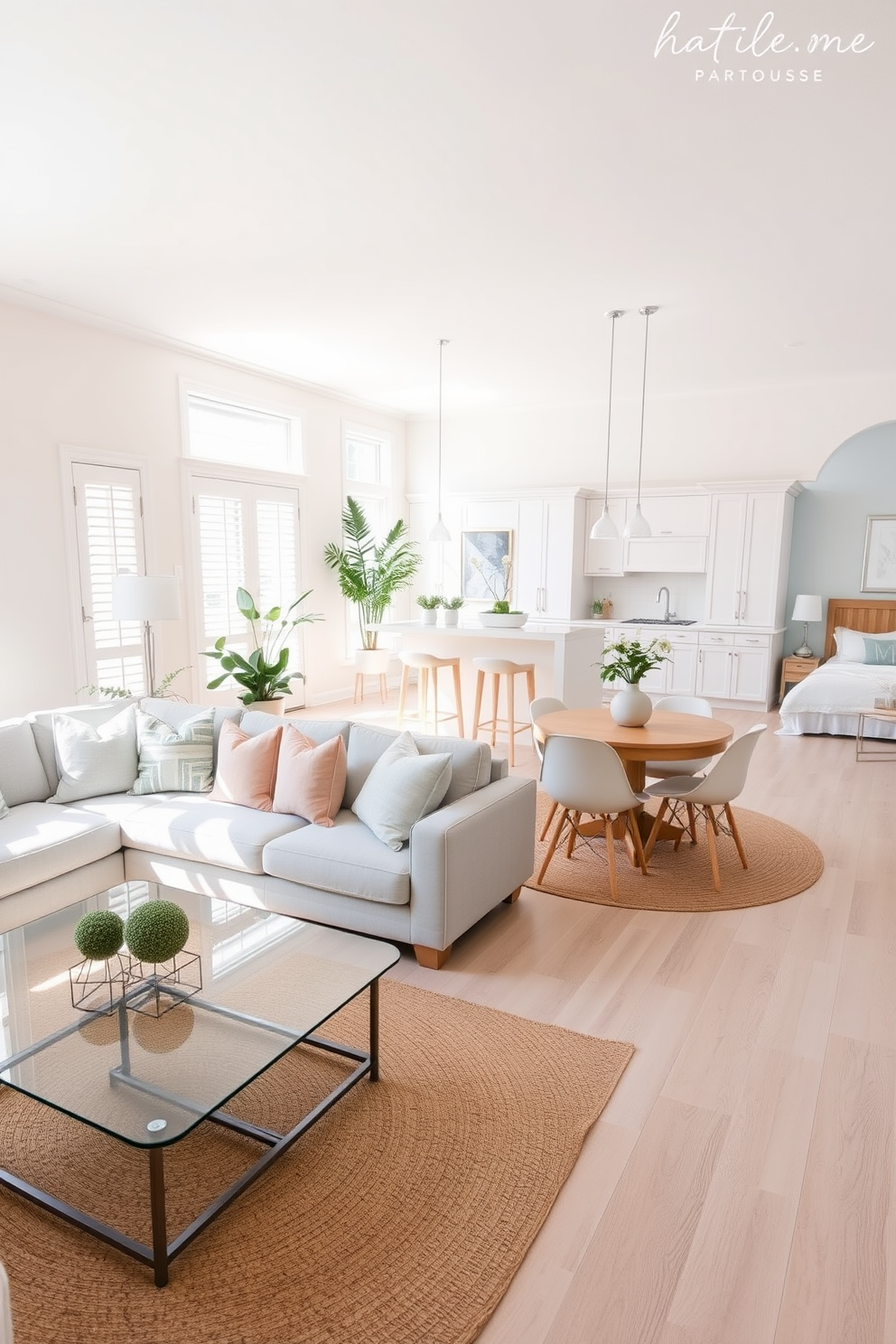 A bright and airy townhouse apartment featuring an open concept living area. The walls are painted in soft white and light beige hues, creating a warm and inviting atmosphere. The living room includes a plush light gray sectional sofa adorned with pastel-colored throw pillows. A sleek glass coffee table sits atop a light jute area rug, complementing the natural light streaming in from large windows. The kitchen boasts white cabinetry with brushed nickel hardware and a spacious island with bar seating. Light wood flooring enhances the sense of space and continuity throughout the apartment. In the dining area, a round wooden table with light-colored chairs is surrounded by soft pendant lighting. A large potted plant adds a touch of greenery, creating a fresh and vibrant ambiance. The bedroom features a light blue accent wall, paired with crisp white bedding and soft gray accents. A minimalist wooden bed frame and bedside tables create a serene and uncluttered space.