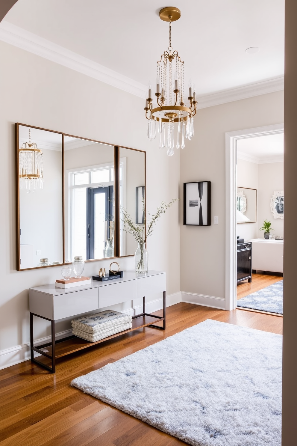 A unique light fixture hangs elegantly from the ceiling, serving as the focal point of the entryway. The walls are adorned with a soft, neutral paint, complemented by a stylish console table beneath the light. A large mirror reflects the light fixture, enhancing the space's brightness and depth. Potted plants are strategically placed on either side of the console, adding a touch of greenery and warmth to the townhouse entryway.