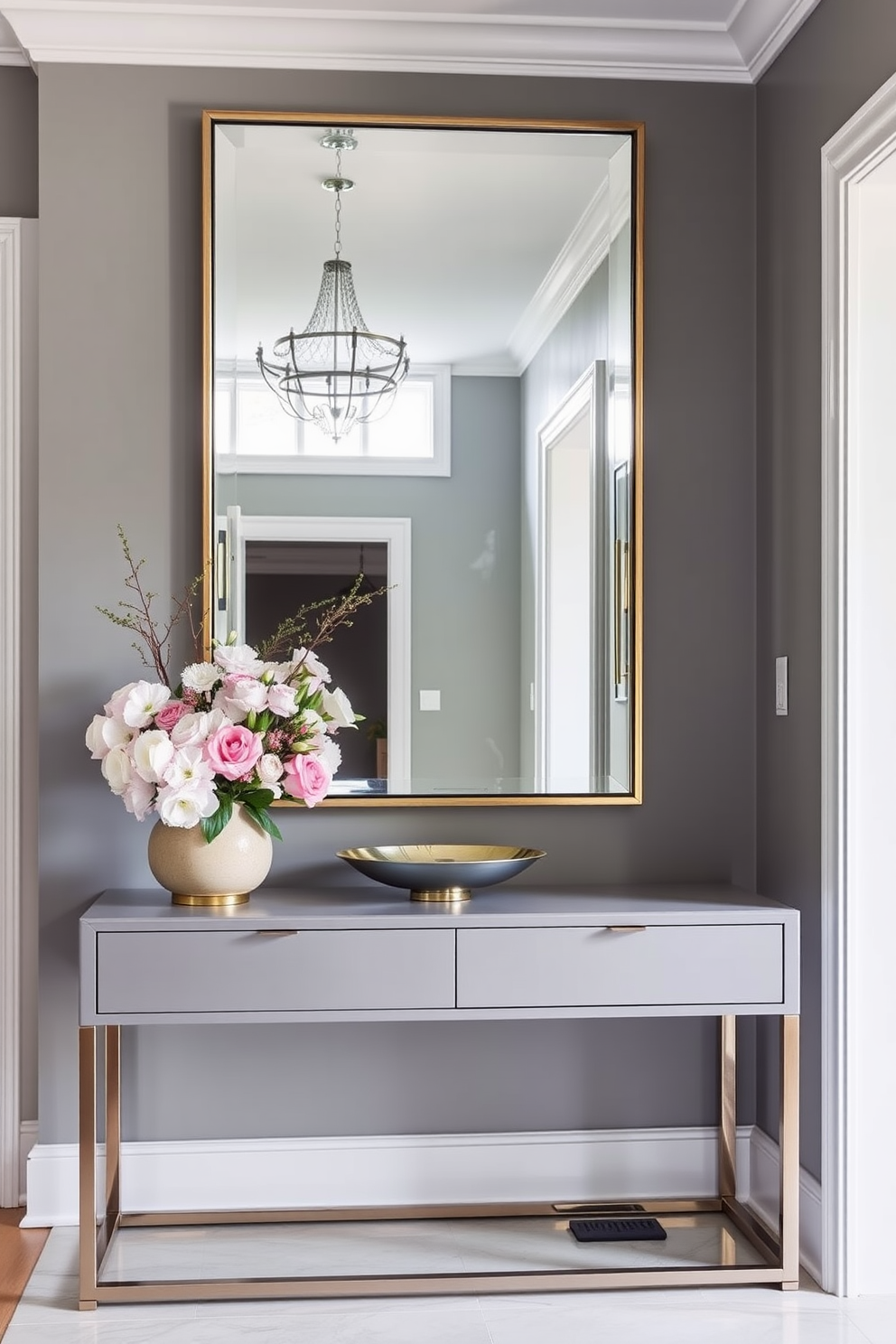 A stylish townhouse entryway featuring a large decorative mirror that enhances light reflection. The walls are painted in a soft gray, complemented by a sleek console table adorned with fresh flowers and a decorative bowl.