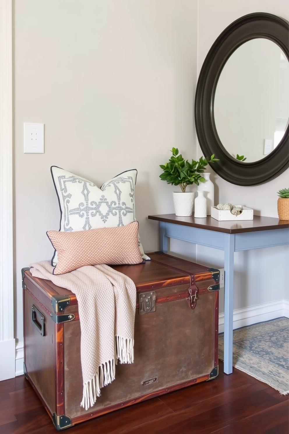 A vintage trunk serves as a unique storage solution in the townhouse entryway. The trunk is placed against the wall, adorned with a cozy throw blanket and a decorative pillow on top. The entryway features a stylish console table with a round mirror above it. A small potted plant sits on the table, adding a touch of greenery to the space.