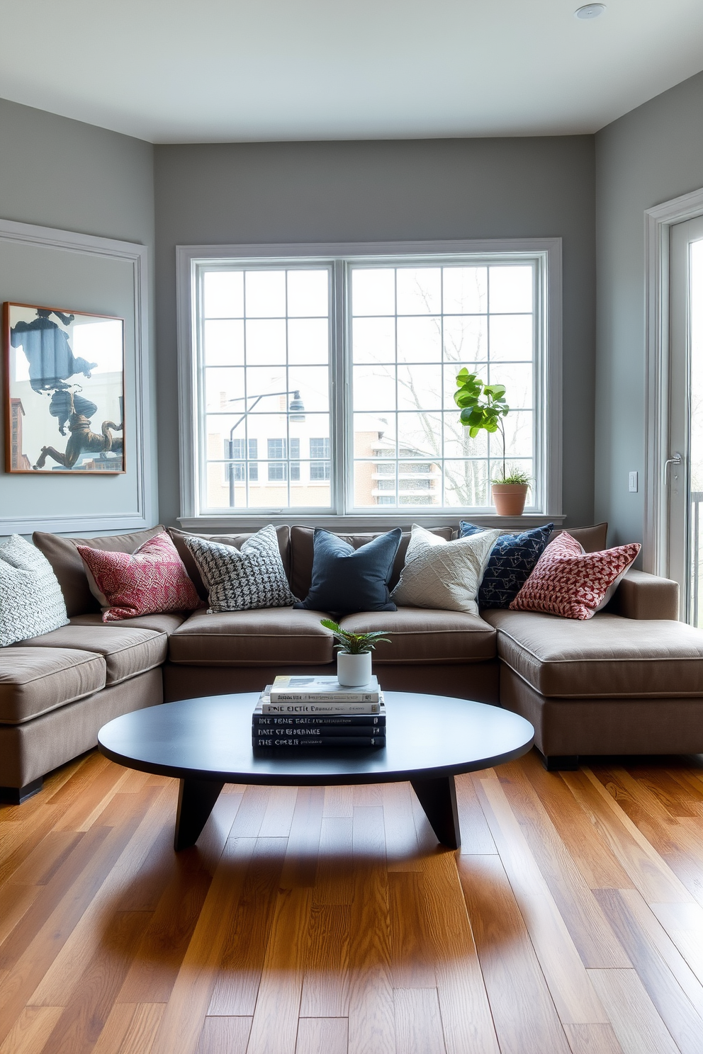 Textured cushions in various hues and patterns are arranged on a plush sectional sofa, creating a cozy and inviting atmosphere. A sleek coffee table sits in front, adorned with a stack of art books and a small potted plant for a touch of greenery. The walls are painted in a soft gray, complementing the warm wooden flooring that adds depth to the space. Large windows allow natural light to flood in, highlighting the carefully curated decor and bringing warmth to the townhouse living room.