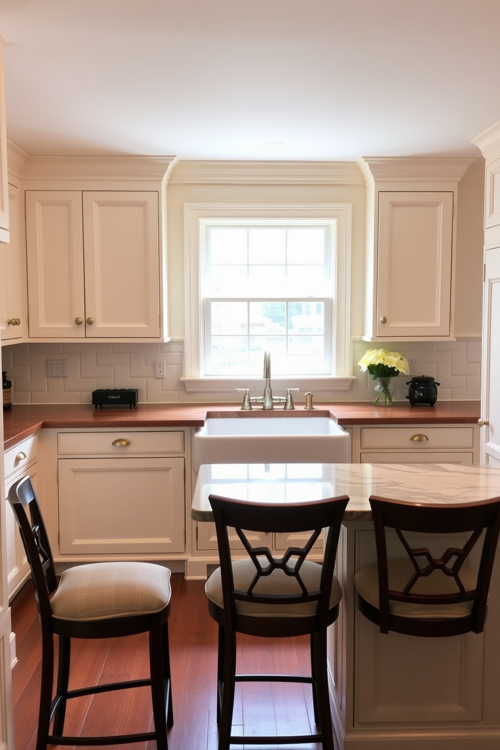 A charming traditional kitchen featuring elegant wainscoting accents that enhance the overall aesthetic. The cabinets are painted in a soft cream color with brass hardware, and the countertops are made of rich dark wood. A large farmhouse sink is centered beneath a window, allowing natural light to flood the space. The kitchen island is topped with a beautiful marble surface and surrounded by comfortable bar stools.