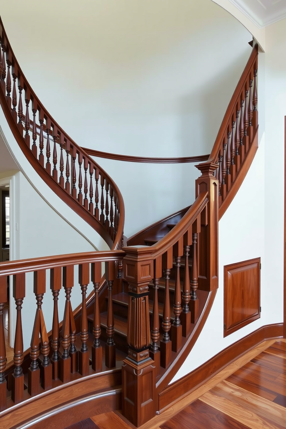 A grand curved staircase gracefully ascends, featuring intricately carved decorative newel posts that add elegance to the design. The balustrade showcases a classic wooden finish, complementing the rich tones of the hardwood flooring below.