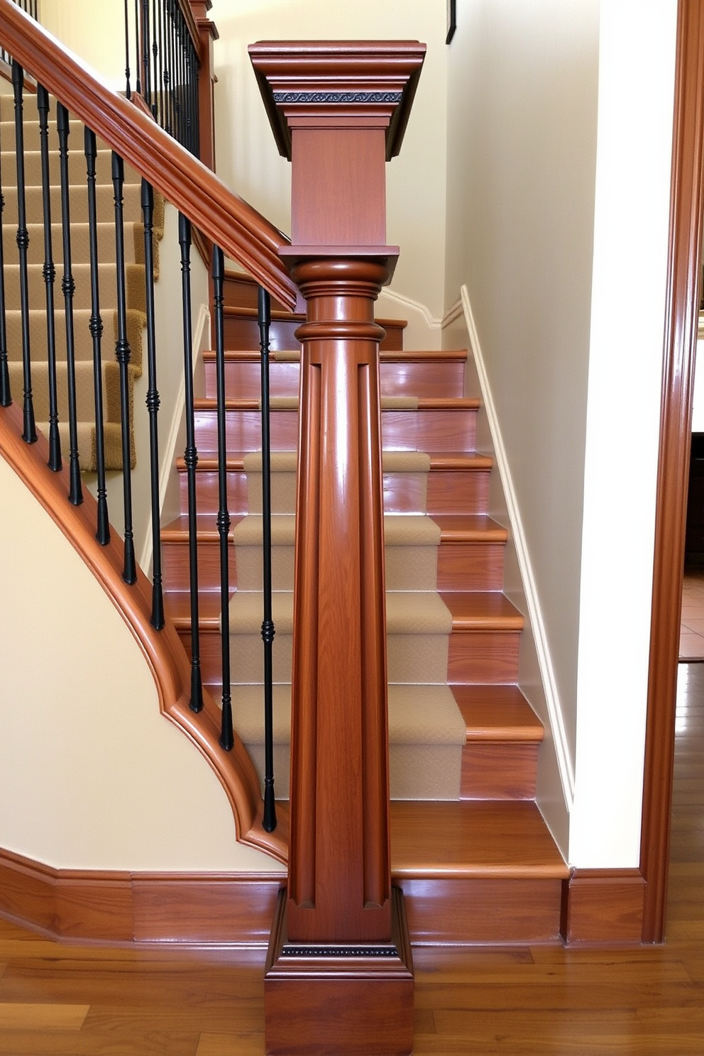 A stately newel post with a decorative cap stands prominently at the base of the staircase. The post is crafted from rich mahogany and features intricate carvings that add elegance to the traditional staircase design. The staircase itself is adorned with polished oak treads and a classic runner that complements the wood tones. Wrought iron balusters line the sides, providing a timeless contrast to the warm hues of the wood.