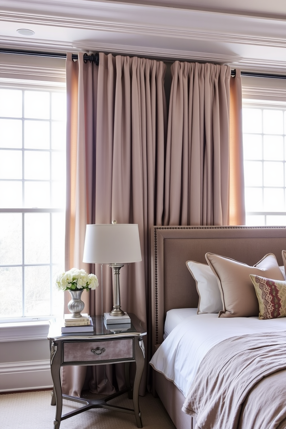 Elegant drapes gracefully frame the large windows, cascading down to the floor in soft, flowing fabric. The color palette features muted tones that complement the overall decor, enhancing the room's serene ambiance. Transitional bedroom design ideas blend contemporary and traditional elements seamlessly. A plush upholstered headboard pairs beautifully with a vintage-inspired nightstand, creating a harmonious and inviting space.