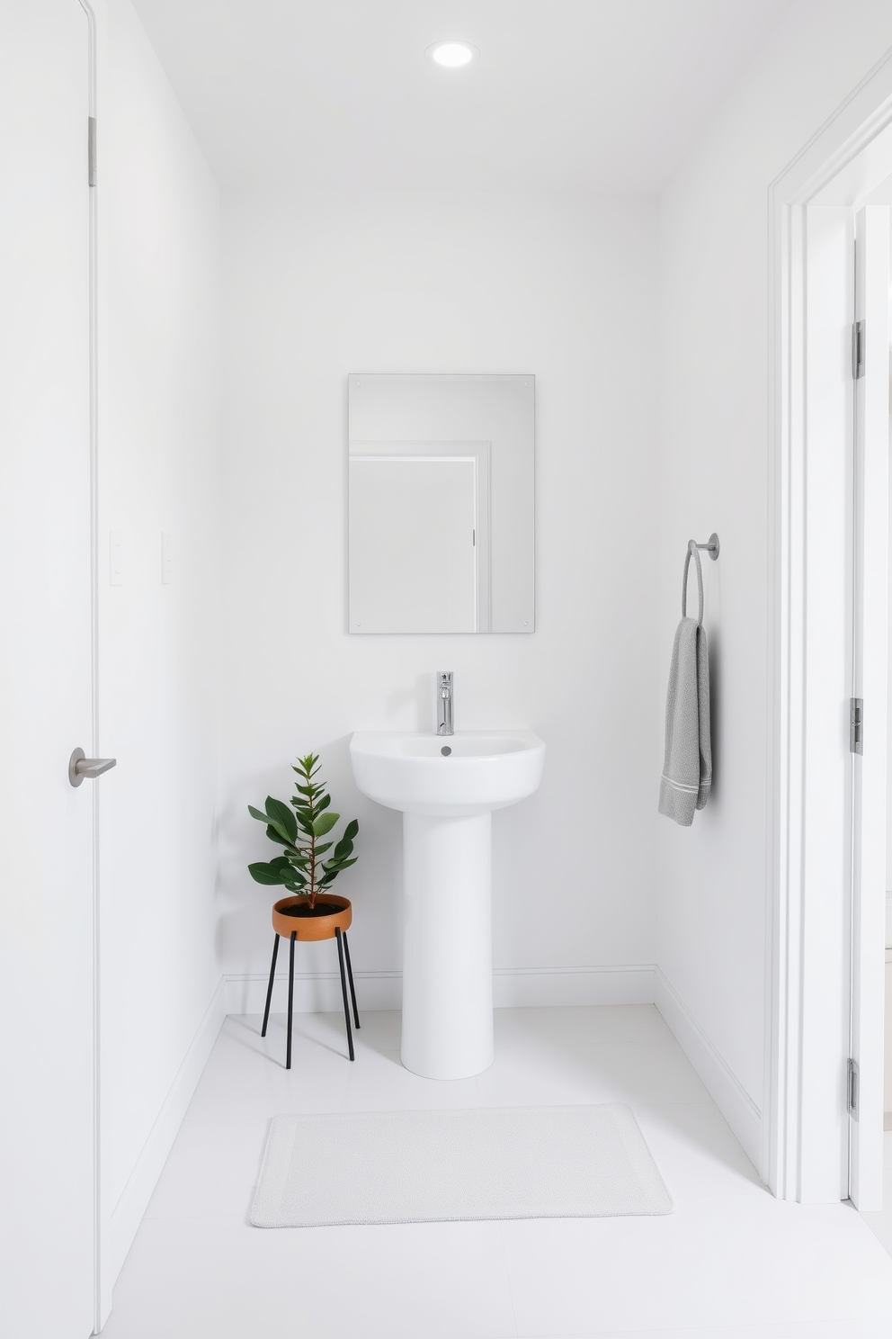 A stylish powder room featuring minimalist design with clean lines. The space is adorned with a sleek pedestal sink and a wall-mounted faucet, complemented by a large frameless mirror that enhances the sense of openness. The walls are painted in a soft white hue, creating a bright and airy atmosphere. A small potted plant adds a touch of greenery, while a simple geometric rug anchors the space with subtle texture.