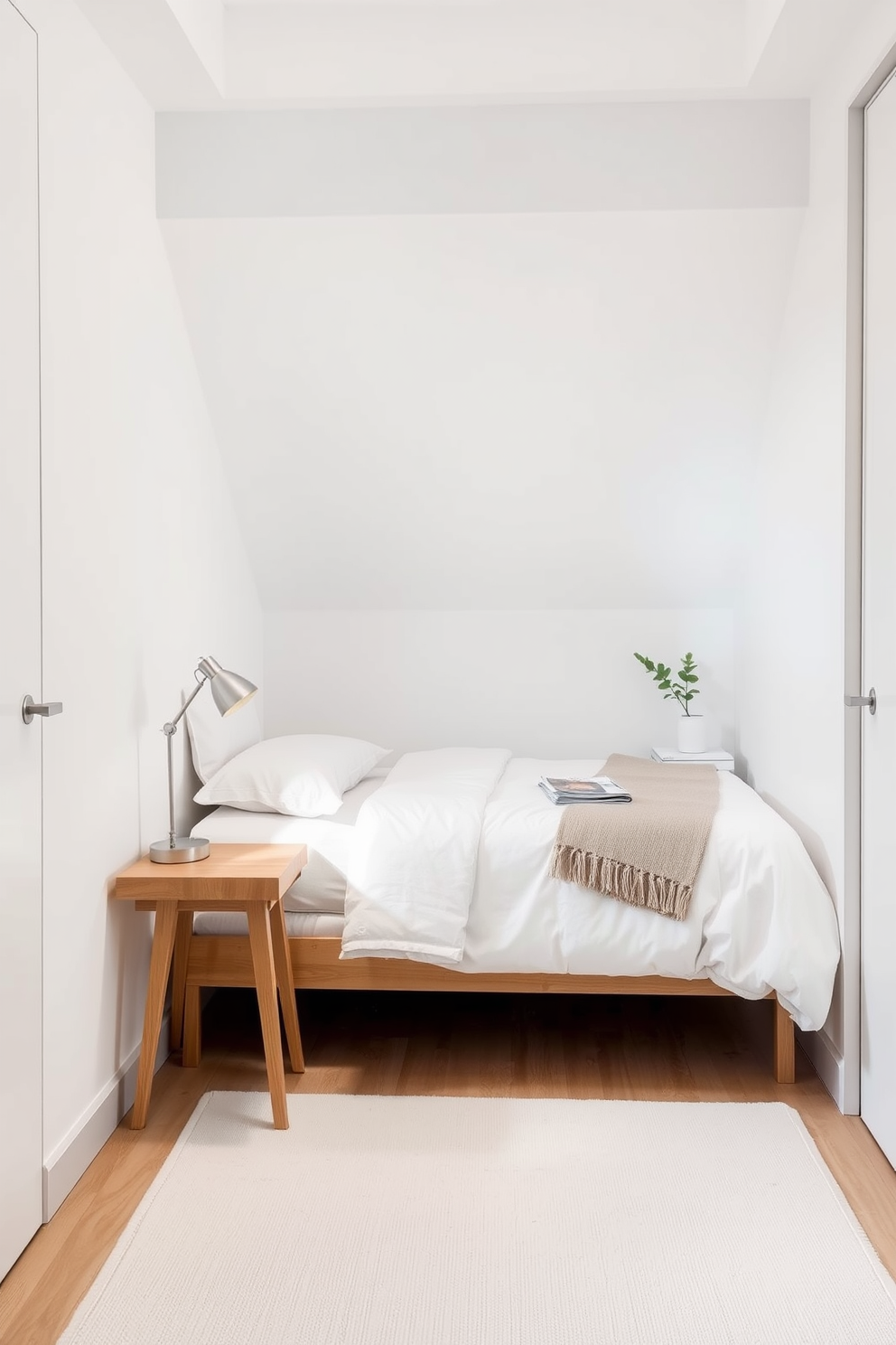 A very small bedroom featuring a minimalist design with a soft white color palette. The walls are adorned with light gray accents, and a compact bed with crisp white bedding is positioned against one wall. A sleek nightstand in natural wood sits next to the bed, topped with a simple lamp and a small potted plant. The floor is covered with a light-colored area rug, adding warmth to the space while maintaining an airy feel.