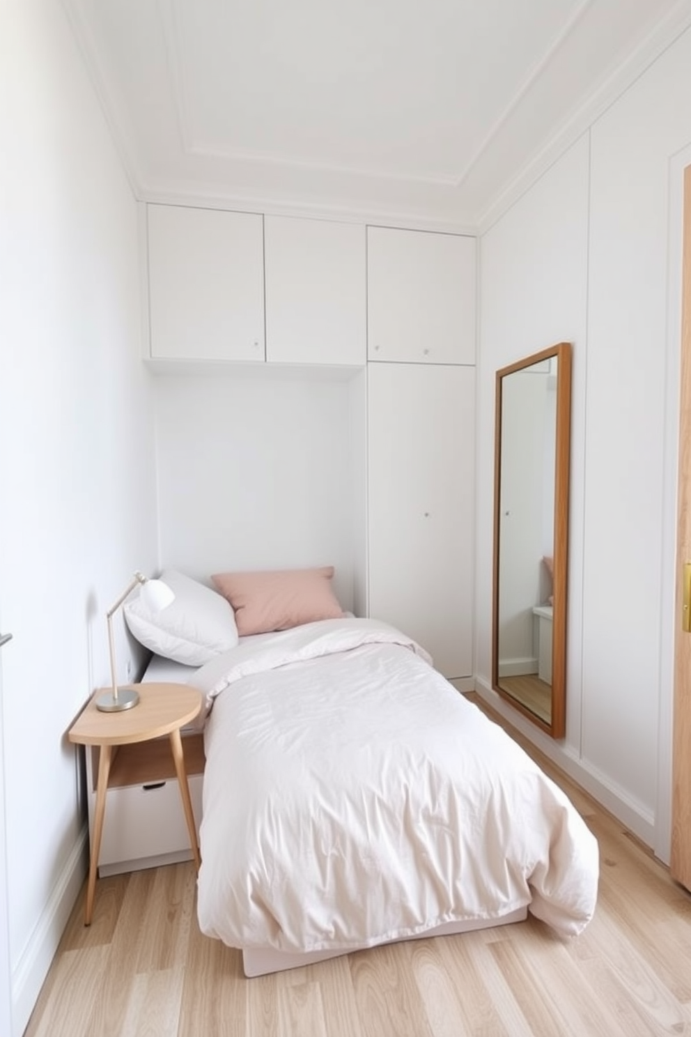 A very small bedroom designed with light colors to create an open and airy feel. The walls are painted in soft white, and the bedding features pastel shades to enhance the brightness of the space. A compact bed with built-in storage is positioned against one wall, maximizing floor space. A small nightstand with a minimalist lamp sits beside the bed, and a large mirror is mounted on the opposite wall to reflect light and create the illusion of depth.