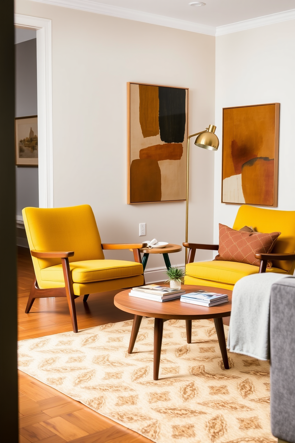 A cozy living room featuring mid-century modern accent chairs with clean lines and tapered legs. The chairs are upholstered in a vibrant mustard yellow fabric, positioned around a round wooden coffee table. The walls are adorned with abstract art in earthy tones, complementing the warm wood flooring. A stylish floor lamp with a brass finish stands beside one of the chairs, creating a welcoming reading nook.