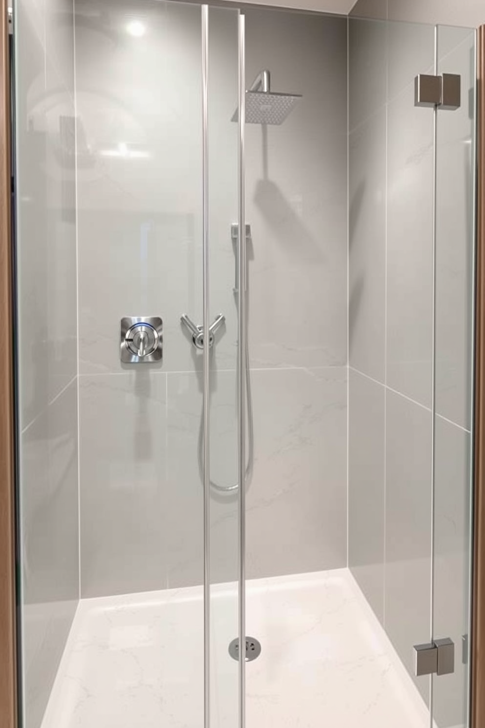 A sleek walk-in shower features smart shower controls seamlessly integrated into the wall for modern convenience. The glass enclosure allows for an open and airy feel, complemented by large format tiles in a neutral color palette.