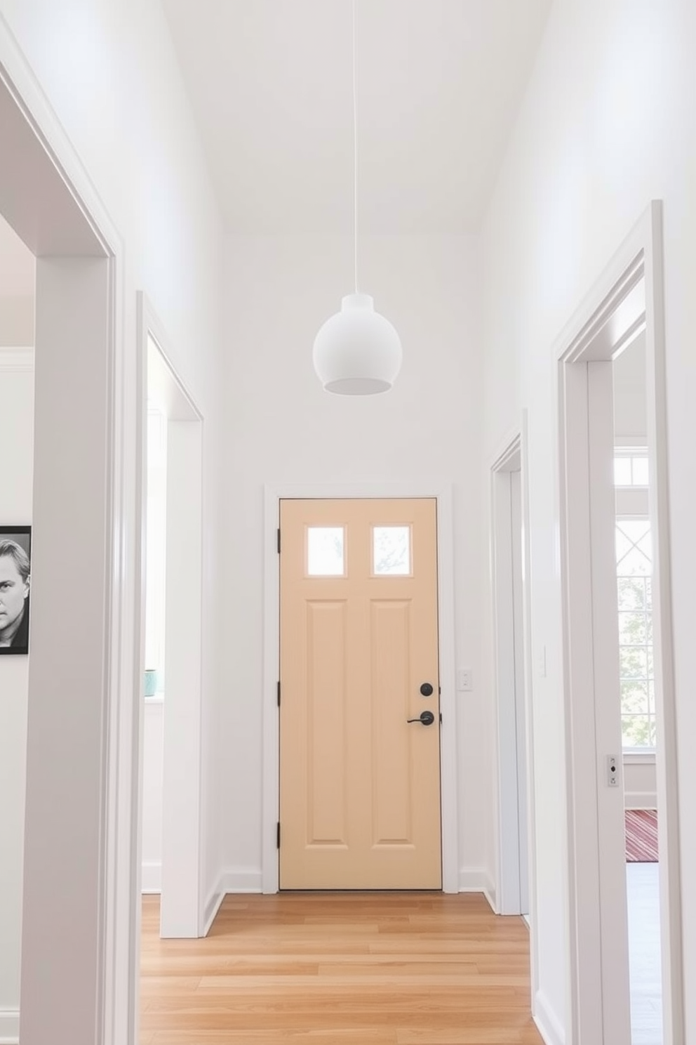 A bright and airy foyer features a minimalist white pendant light fixture hanging gracefully from the ceiling. The walls are painted in a soft white hue, and the floor is adorned with light hardwood, creating a seamless and inviting entryway.