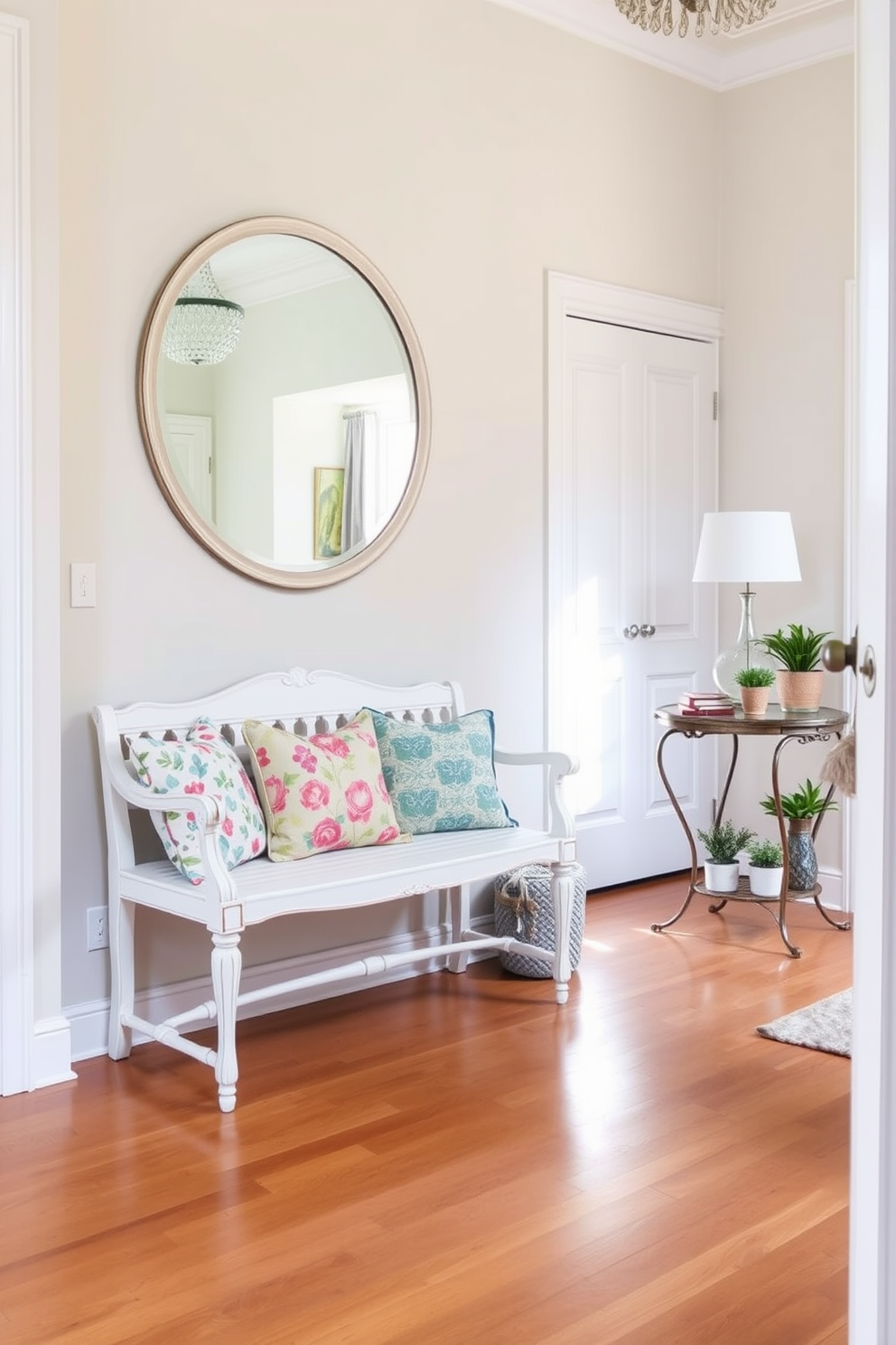 A vintage white bench is placed against the wall, adorned with a variety of colorful cushions that add a playful touch. The flooring is a warm wood, and a large round mirror hangs above the bench, reflecting natural light from the nearby window. The foyer features soft pastel walls that create an inviting atmosphere. A decorative console table stands next to the bench, topped with a few carefully arranged potted plants and a stylish lamp.