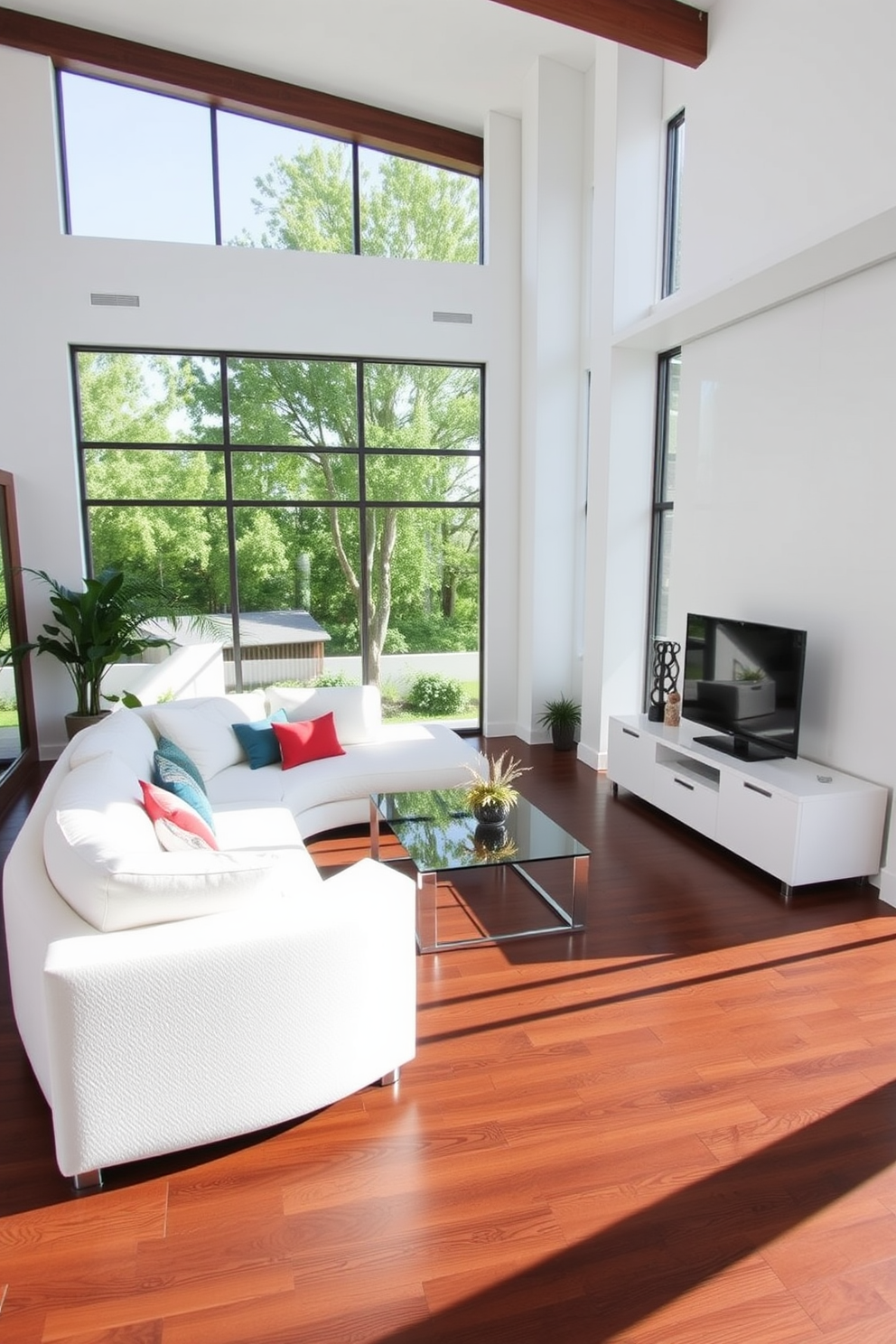 Bright white furniture contrasts elegantly with the rich tones of dark hardwood flooring. The space features a spacious layout with a plush white sectional sofa, accented by vibrant throw pillows and a sleek glass coffee table. Large windows allow natural light to flood the room, enhancing the airy atmosphere. A minimalist white entertainment unit sits against the wall, complemented by tasteful decor and greenery.