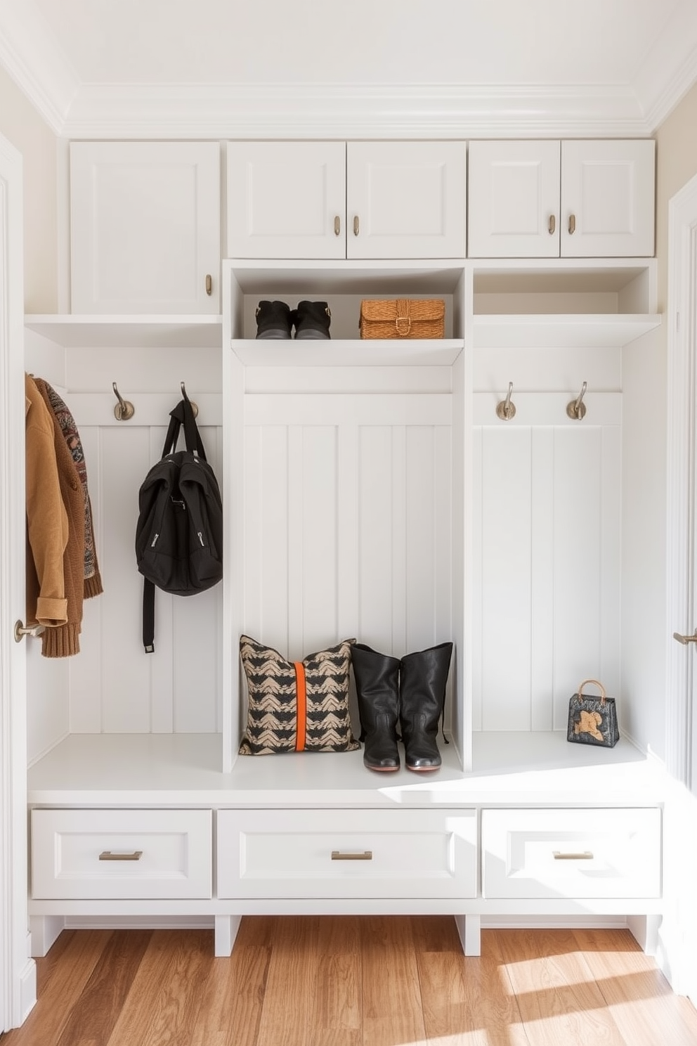 A white built-in bench with storage underneath is positioned against the wall in a mudroom. The bench features soft cushions and is surrounded by hooks for coats and bags, creating a functional and stylish entryway space. The mudroom is designed with light gray walls and a durable tile floor that complements the white bench. Natural light floods the area through a nearby window, enhancing the welcoming atmosphere of the space.