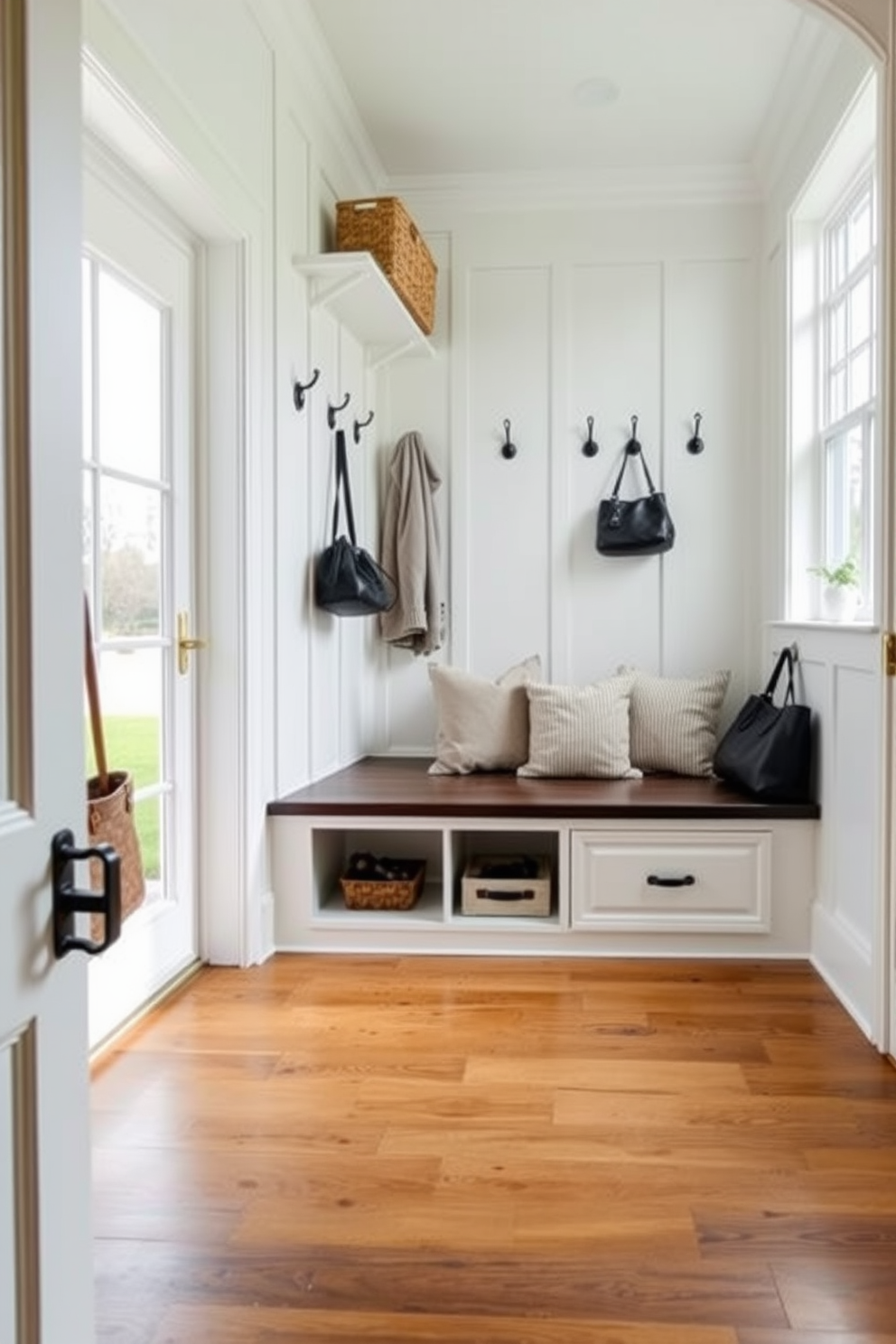 A cozy mudroom featuring built-in seating with hidden storage compartments underneath. The walls are painted a soft white, complemented by a durable wood floor and stylish hooks for coats and bags. The seating area is adorned with plush cushions in neutral tones, creating a welcoming space. Natural light floods in through a large window, highlighting the organized storage solutions and decorative elements.