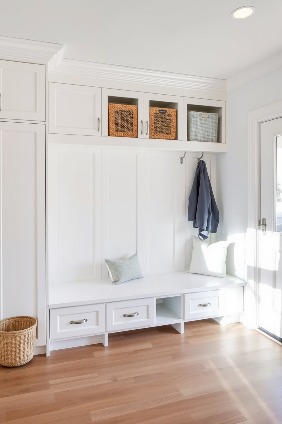 A bright and airy mudroom features floor to ceiling cabinetry for optimal organization. The cabinetry is painted in a soft white hue, complemented by a sleek bench with plush cushions for comfort.