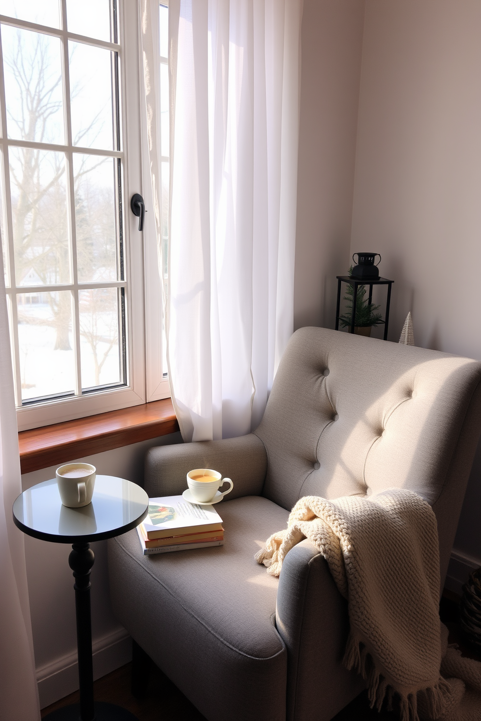 A cozy reading nook is set up by a large window, featuring a plush armchair upholstered in soft gray fabric. A small side table holds a steaming cup of tea and a stack of books, while a warm throw blanket drapes over the arm of the chair. The window is adorned with sheer white curtains that allow natural light to filter in, creating an inviting atmosphere. Winter-themed decorations, such as a small evergreen arrangement and a decorative lantern, add seasonal charm to the space.