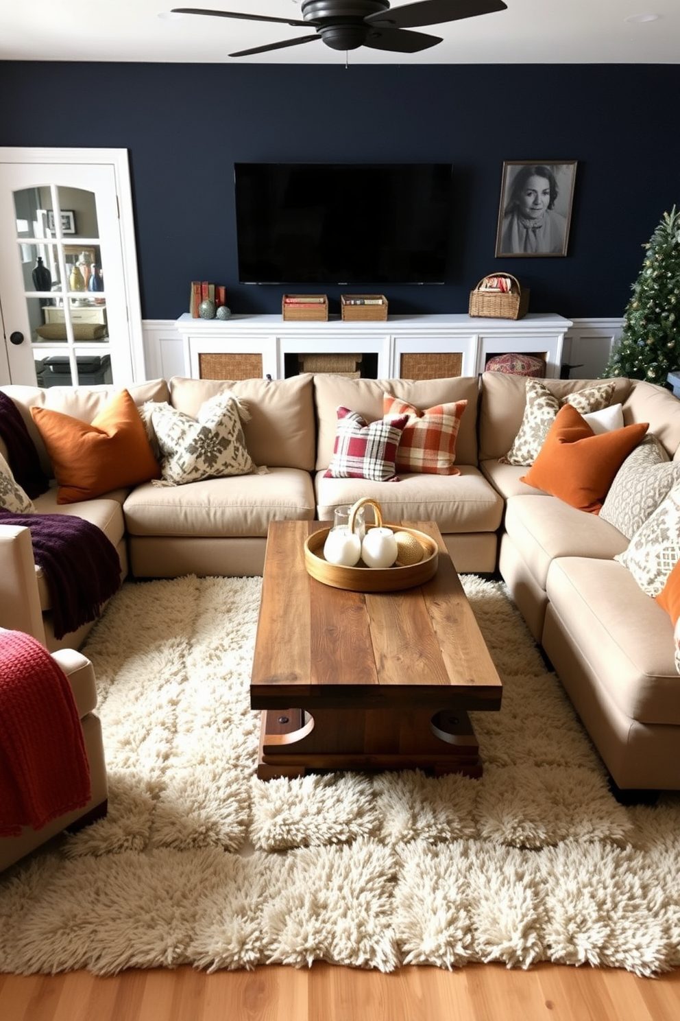 Cozy winter game room featuring a large sectional sofa adorned with seasonal throw pillows in rich textures and warm colors. The walls are painted a deep navy, and a rustic wooden coffee table sits in the center, surrounded by soft, plush rugs.