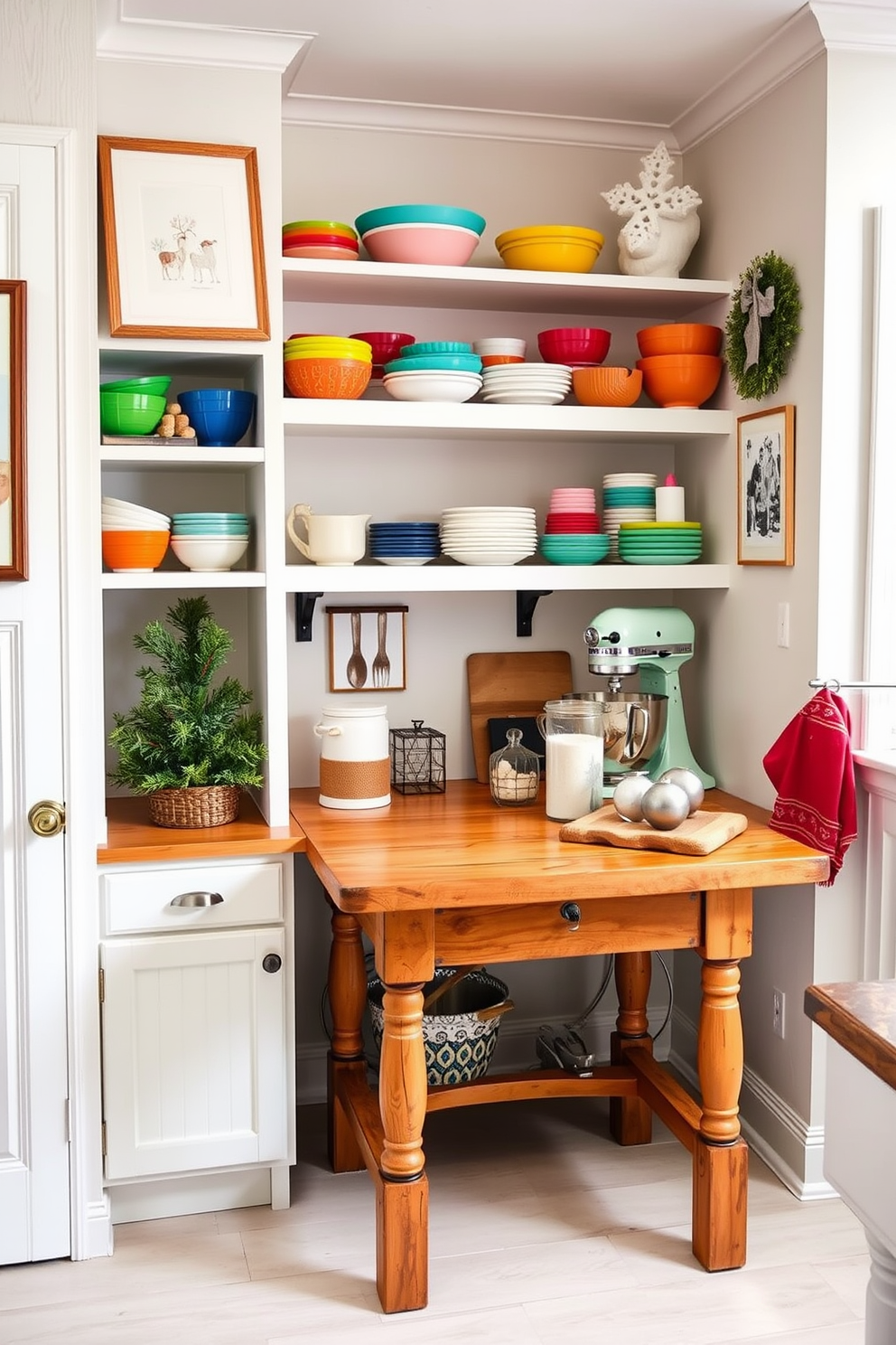 A cozy baking corner is nestled in a bright and airy kitchen. The space features open shelving stocked with colorful baking supplies, mixing bowls, and a stand mixer. A rustic wooden table serves as the centerpiece, adorned with a flour canister and measuring cups. The walls are decorated with winter-themed art, and a small evergreen tree adds a festive touch.