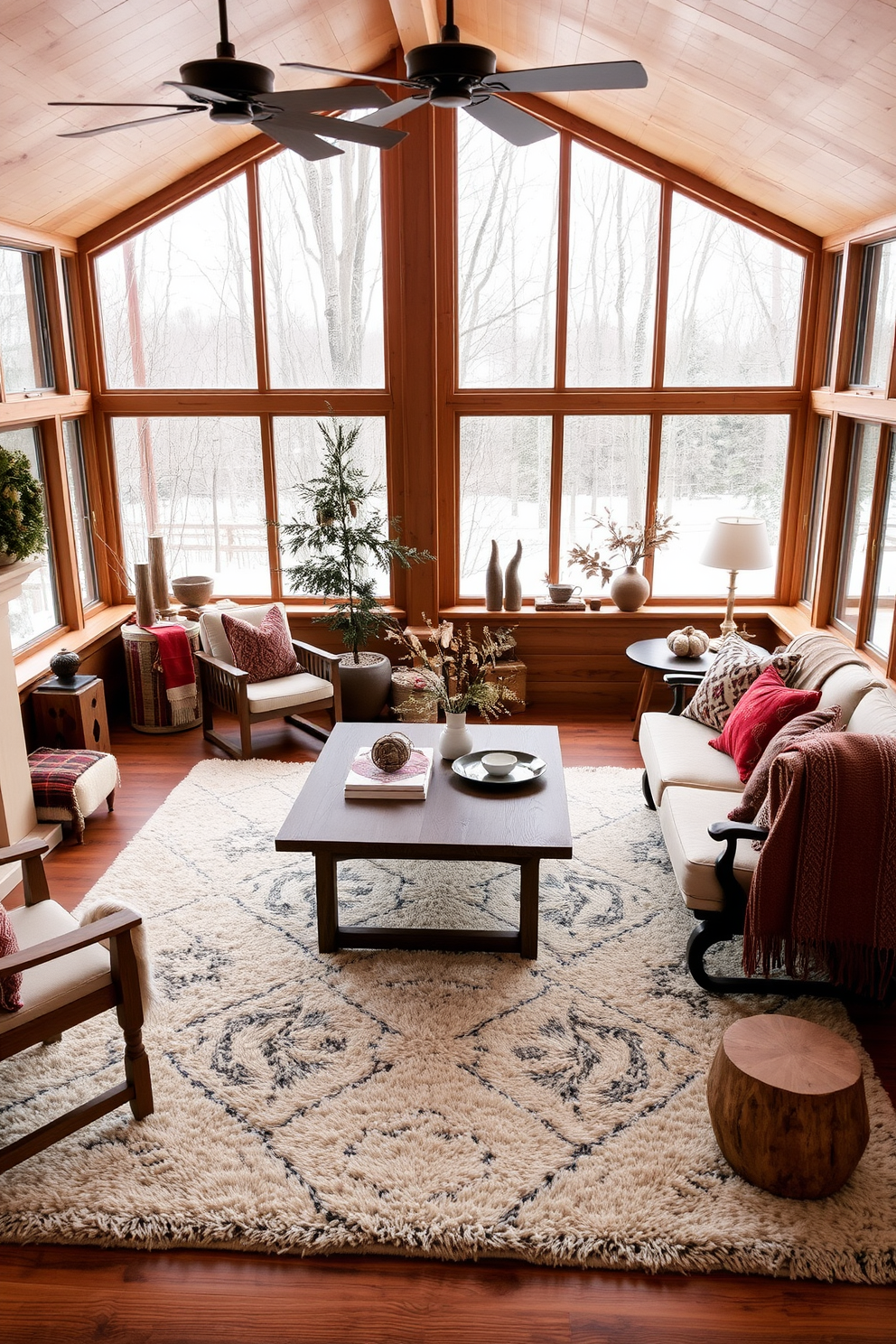 A bright winter sunroom filled with natural light. The walls are painted a soft white, and large windows draped with sheer blue curtains frame the view of the snowy landscape outside. A cozy seating area features a plush white sectional sofa adorned with blue and white patterned throw pillows. A rustic wooden coffee table sits in the center, topped with a few decorative books and a small potted plant.