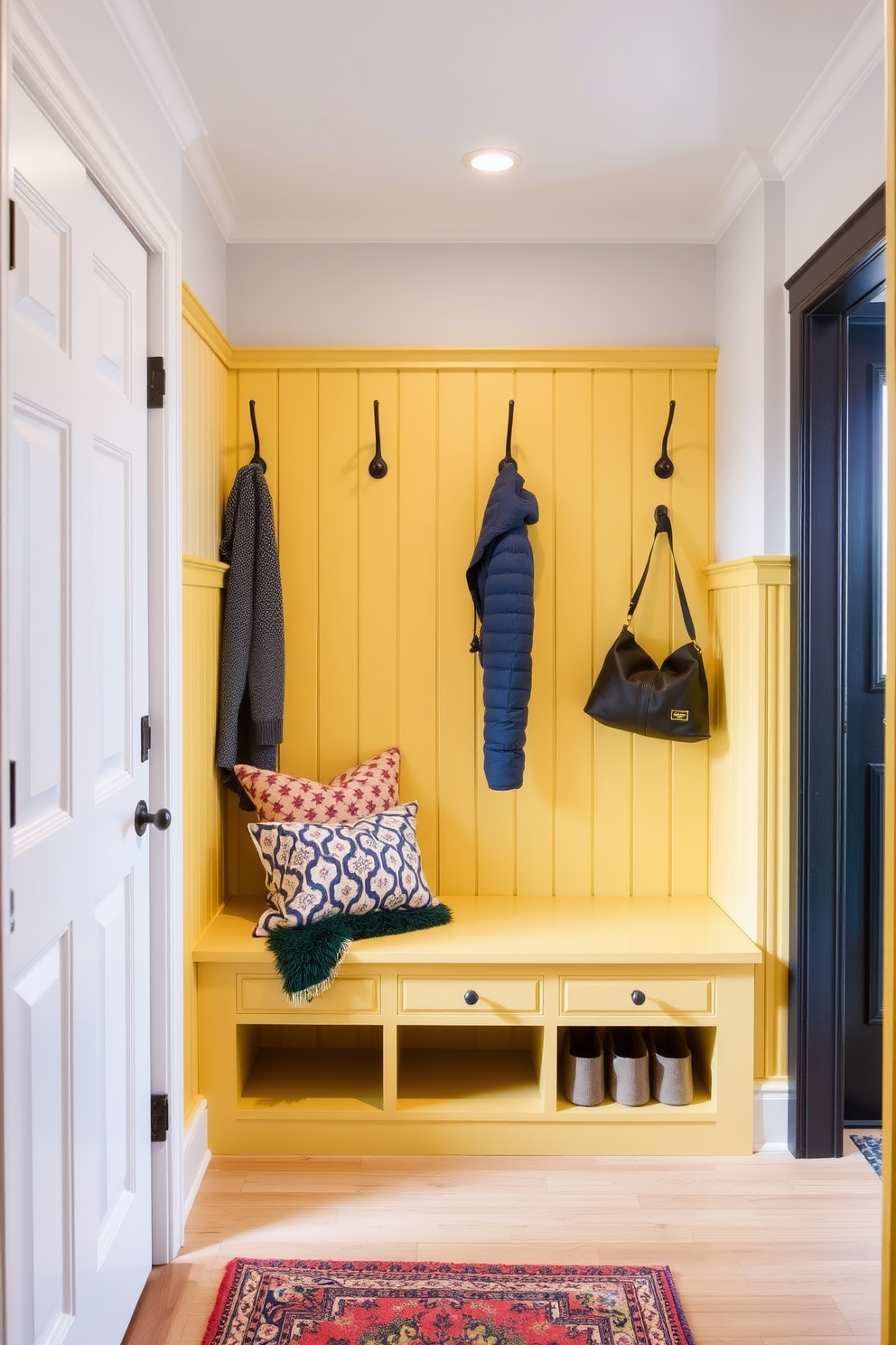 A charming mudroom featuring yellow wainscoting that adds a pop of color and warmth. The space includes a built-in bench with storage underneath and hooks for coats and bags on the wall.